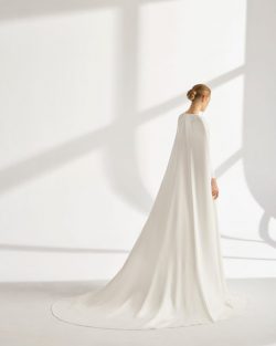 Préndate de Rima, un vestido de dos piezas formado por un traje y una capa de crepé fluida. Una boda eclesiástica en otoño es el marco ideal para lucir este modelo de línea A y escote de pico. Su sencilla manga larga compensa a la perfección la espalda descubierta y la cintura bordada. Tiendas de vestidos de Novia en Toledo, El Clavel