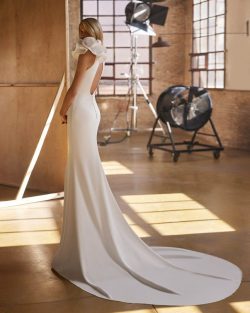 Vestidos de novia 2025 en Toledo. El Clavel. Vestido de novia de dos piezas, de corte sirena y estilo elegante, confeccionado en crepé. Presenta un escote halter, una espalda lágrima sin mangas y una capa de georgette con un lazo. Un delicado conjunto Aire Atelier.