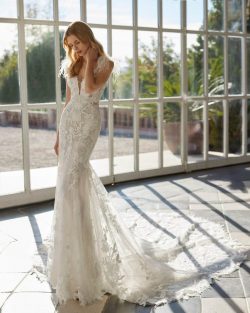 Modelo Vaveri - Vestido de novia largo, de corte sirena y estilo romántico, confeccionado en encaje. Se completa con un escote en V, una espalda abierta y tirantes con plumas. Un modelo de ensueño Aire Barcelona.. Tiendas de vestidos de novia en Toledo el clavel