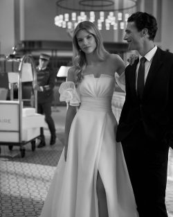 Aire Barecelona en Toledo en El Clavel Colección vestidos de novia 2025 en El Clavel Toledo Vestido de novia largo, con silueta en línea A y estilo romántico, confeccionado en garza. Disfruta de un escote palabra de honor y manga con volantes extraíble. Un exclusivo modelo Aire Barcelona