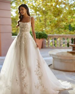 Modelo Inara - Vestido de novia largo, con silueta en línea A y estilo romántico, confeccionado en encaje y falda en tul. Se completa con un escote cuadrado, una espalda abotonada y tirantes. Tiendas de vestidos de Novia en Toledo , El Clavel
