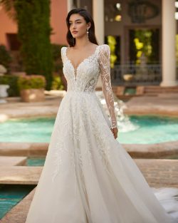 Modelo Inelly - Vestido de novia largo, con silueta en línea A y estilo romántico, confeccionada en encaje combinado con tul. Deslumbra con un escote profundo, una espalda abotonada y tirantes con mangas extraíbles. Tiendas de vestidos de novia en Toledo el clavel