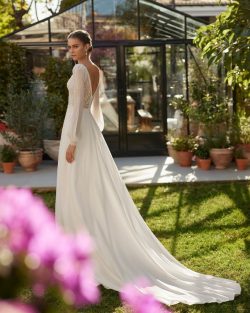 Modelo Ulissa - Vestido de novia largo de estilo elegante, confeccionado en crepé combinado con encaje y pedrería. Muestra un escote redondo, una espalda ilusión, manga abullonada y una falda con abertura lateral. Un modelo de ensueño Aire Boho. Tiendas de vestidos de novia en Toledo . El Clavel